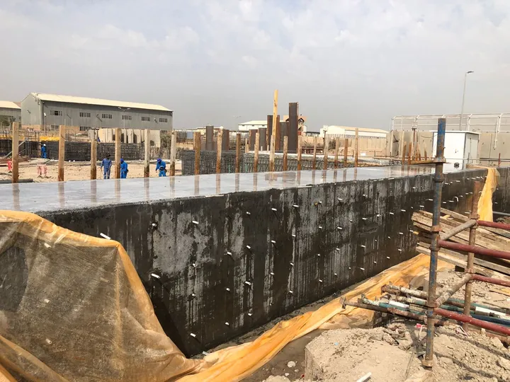 Cast concrete structure surrounded by formwork and site crews.
