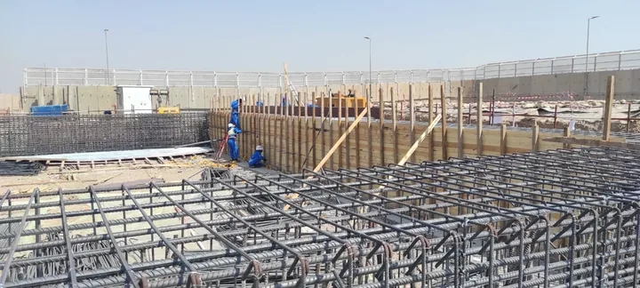 Steel reinforcement grids and bars beside timber formwork.