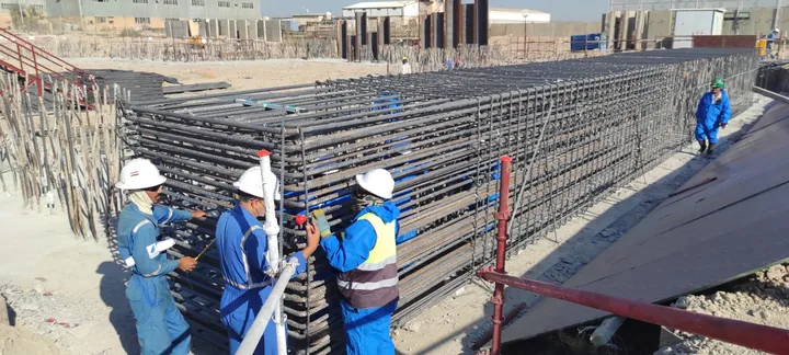 A team in protective equipment beside a steel reinforcement cage.