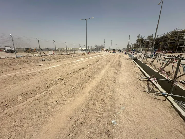 A graded unpaved road bordered by concrete kerbing.