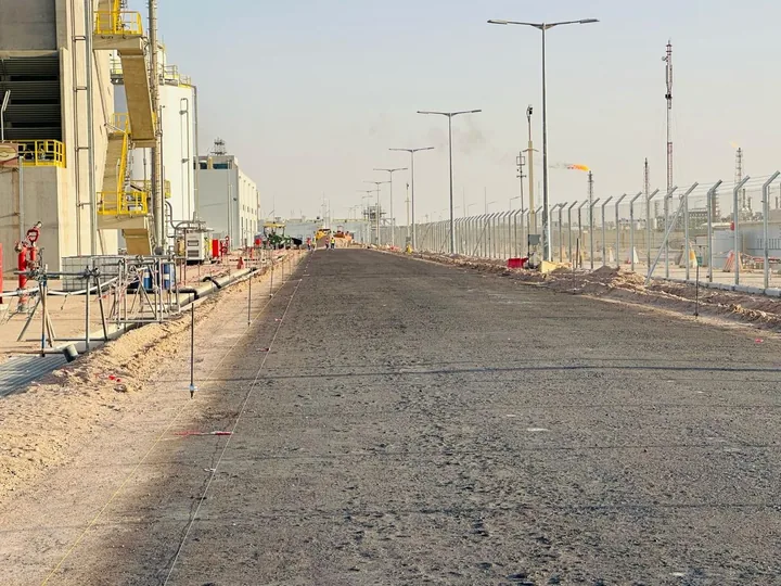 A road with a dark surface layer and setting-out markers along its edges.