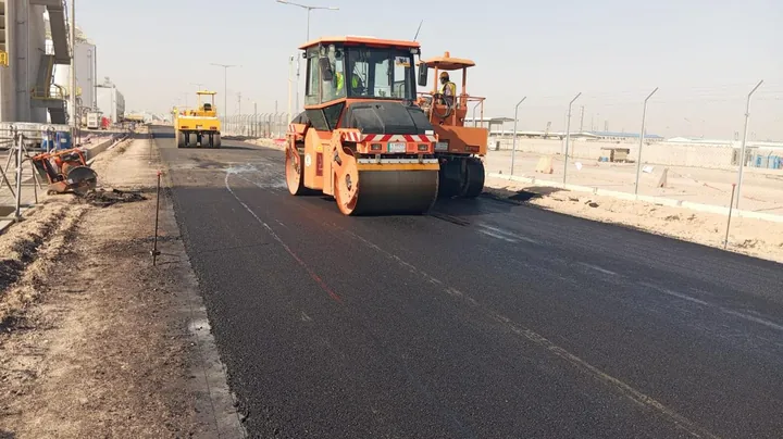 A road roller working on a freshly laid black asphalt layer.