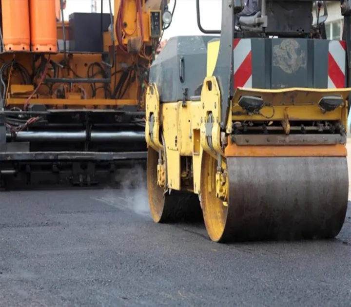 A close view of a yellow roller on an asphalt road surface.